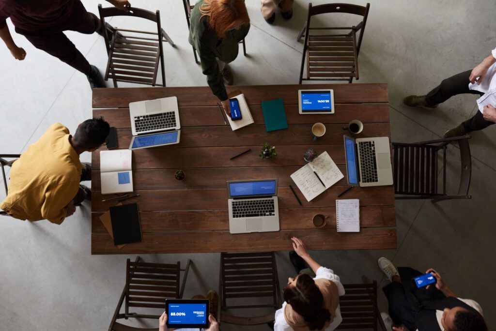 Overhead view of a team working at a wooden table with laptops and tablets