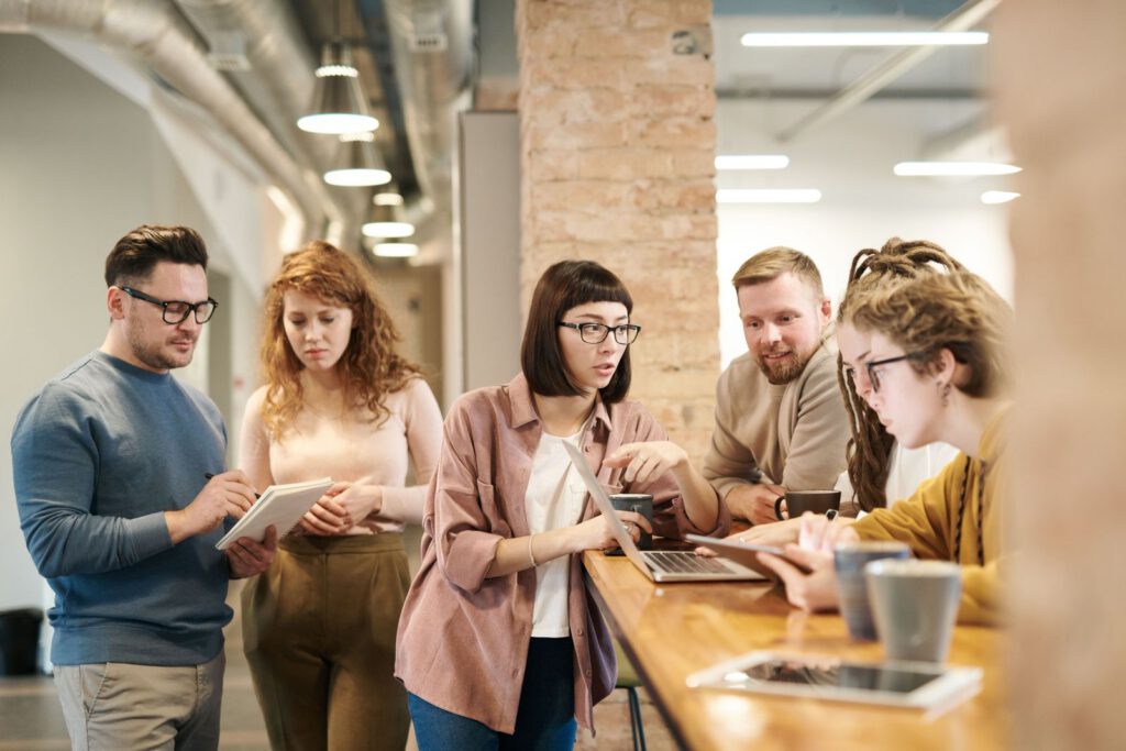 Group of colleagues collaborating around a tablet and a laptop