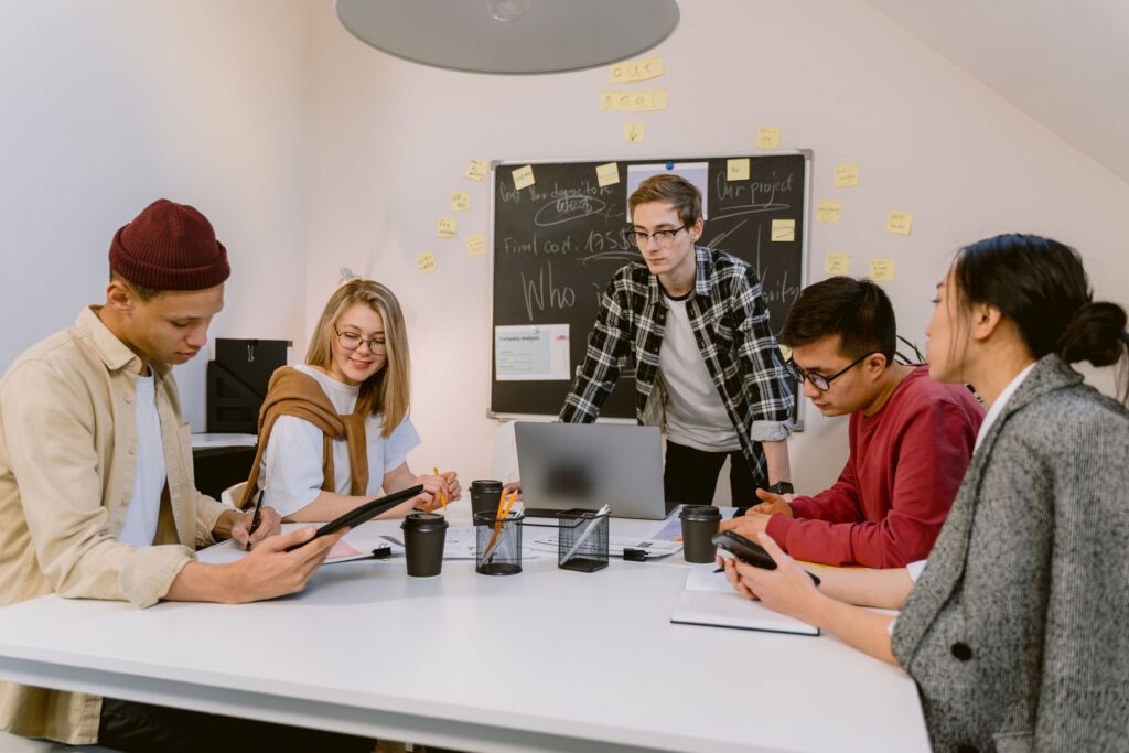 Team brainstorming around a table in front of a chalkboard with sticky notes