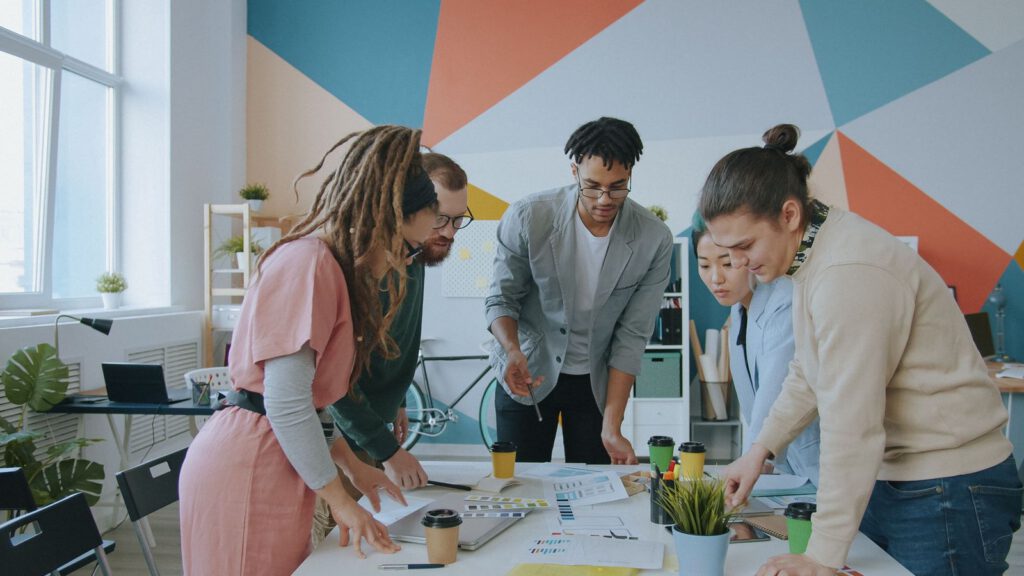 Creative team leaning over a table reviewing design work