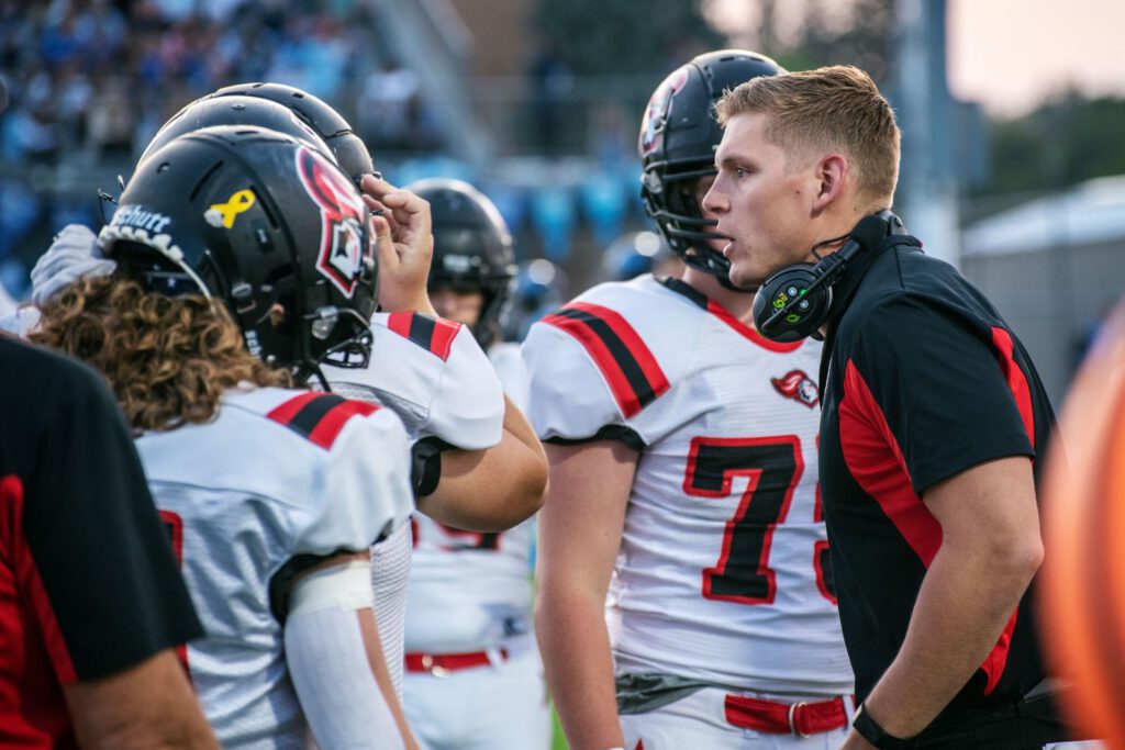 Coach talking with football players on the sideline