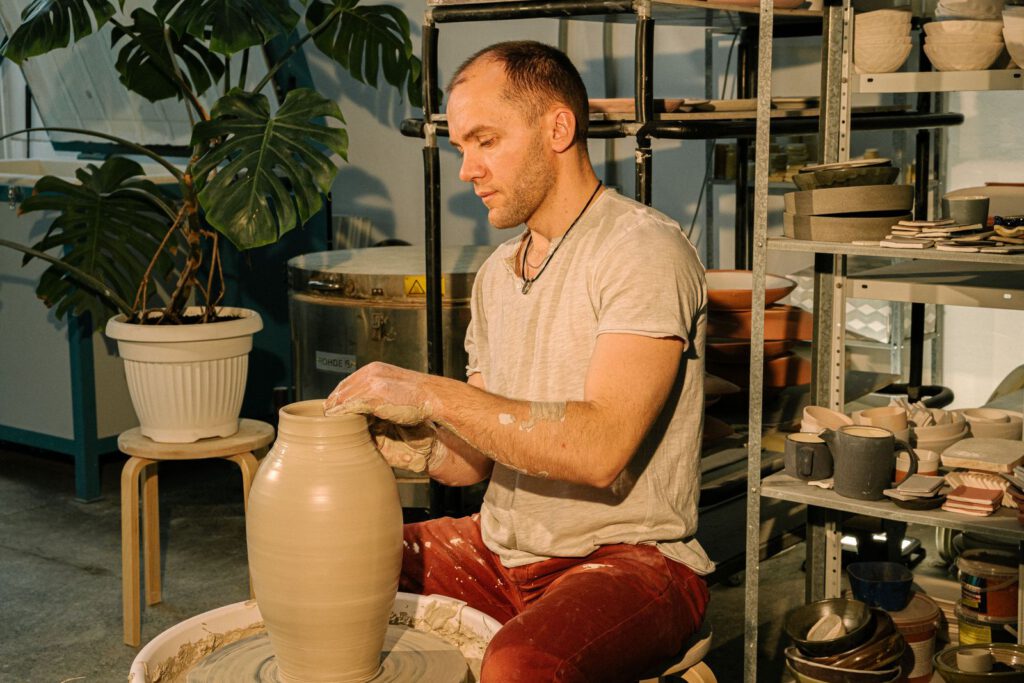 Potter shaping a clay vase on a wheel in a studio