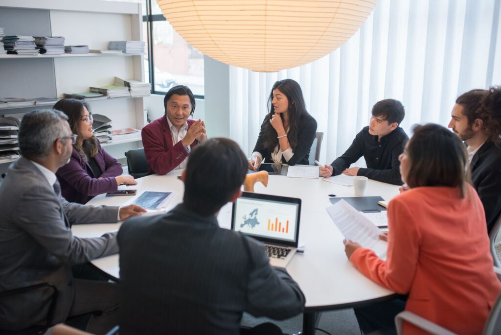 Team meeting around a round table with a laptop showing charts
