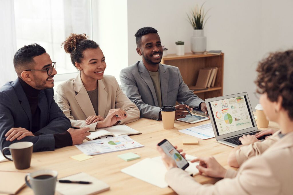 Smiling colleagues in a meeting with charts on a laptop
