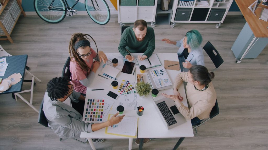 Overhead view of a team working around a table with colour swatches and laptops