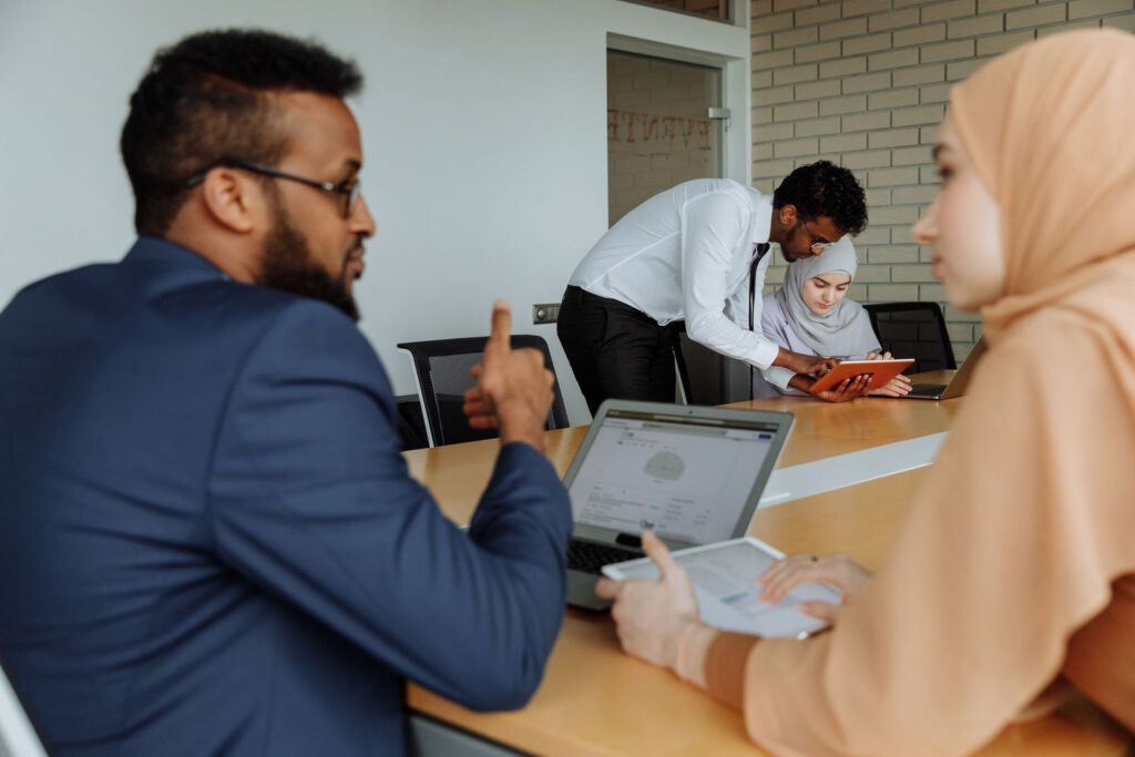 Two colleagues talking over a laptop in an office